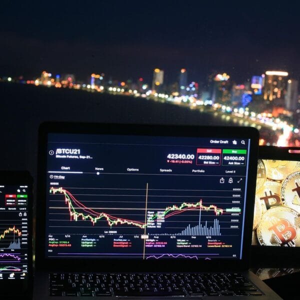 a city view buildings and laptops on a table showing crypto chargtes