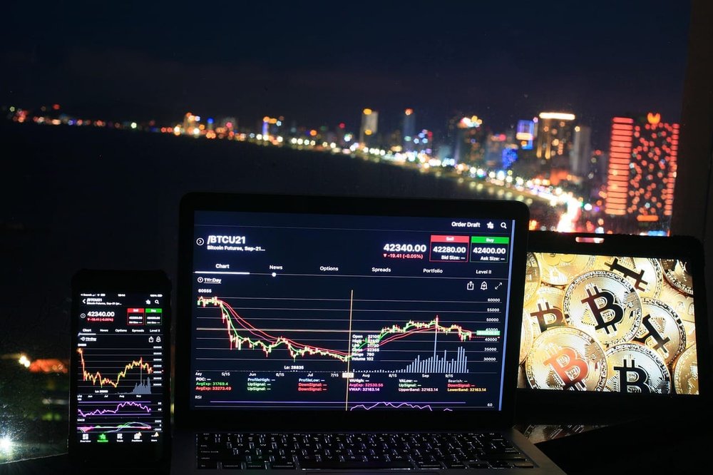 a city view buildings and laptops on a table showing crypto chargtes
